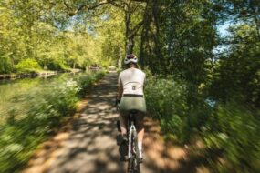 une cyclotouriste au premier plan emprunte une voie verte sur La Voie Bleue, les bords de l'image donnent une impression de vitesse.