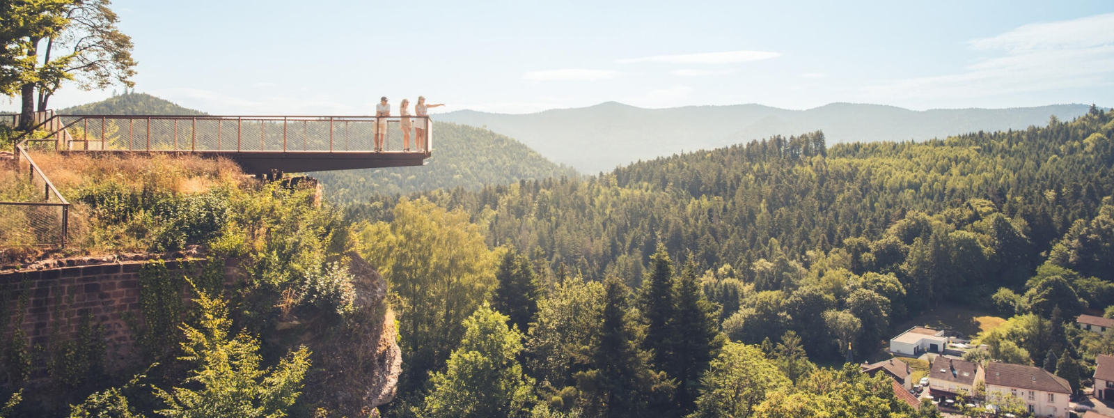 des personnes sur une passerelle au-dessus du vide à pierre-percée en meurthe et moselle avec en arrière-plan les contreforts du massif des vosges